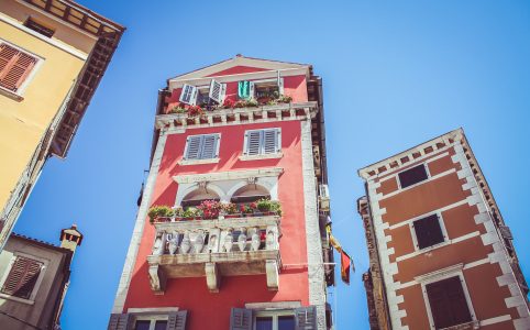 Rotes Haus vor blauem Himmel mit Blümchen am Balkon