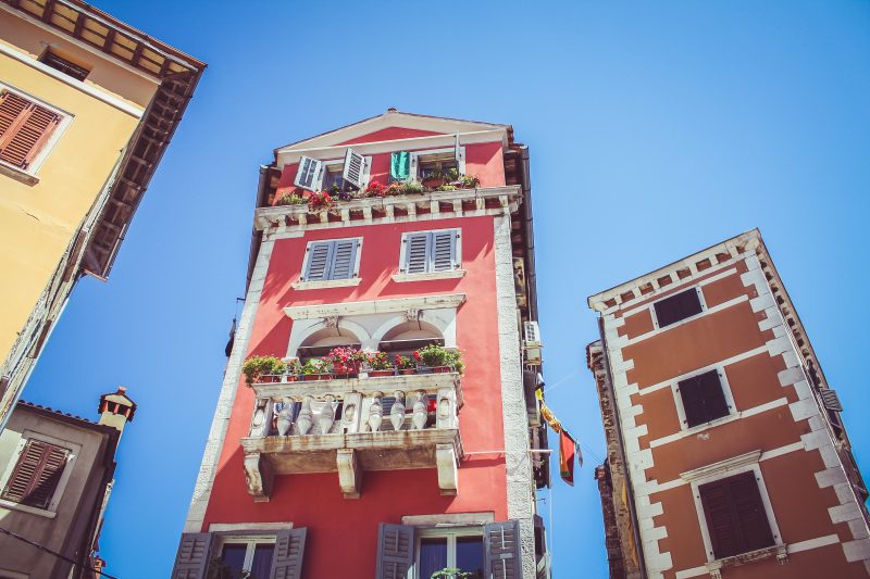 Rotes Haus vor blauem Himmel mit Blümchen am Balkon