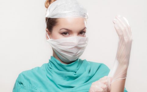 Doktorin zieht sich Handschuhe an