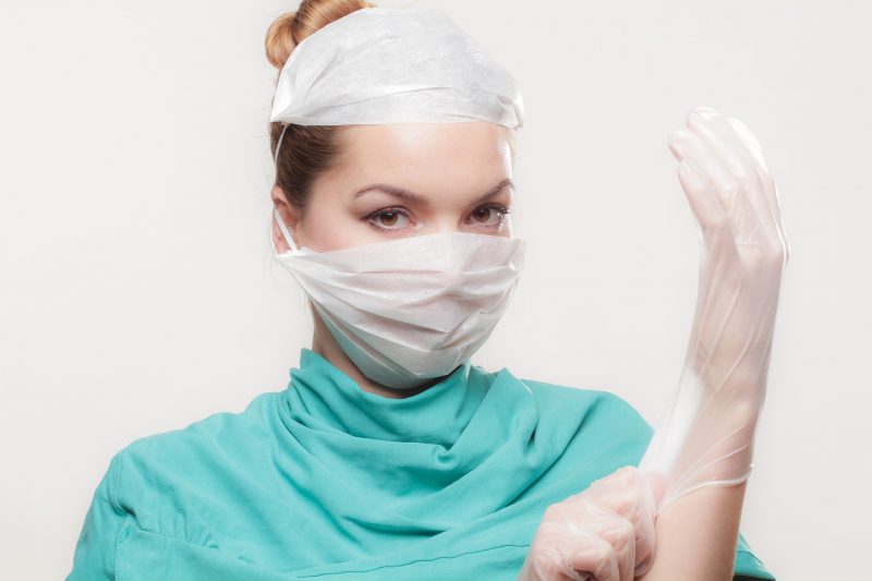 Doktorin zieht sich Handschuhe an